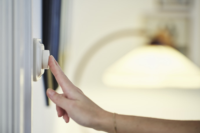  A hand pressing a light button with a lamp in the background