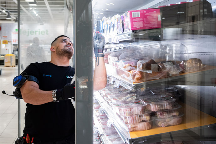 En kyltekniker under en installation av kylar i butiksmiljö