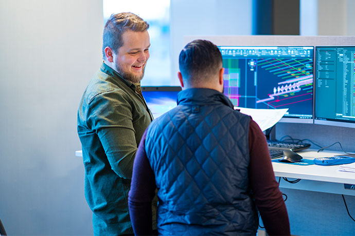  Two employees in an office in front of computer screens
