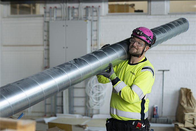  A ventilation technician carrying a ventilation pipe