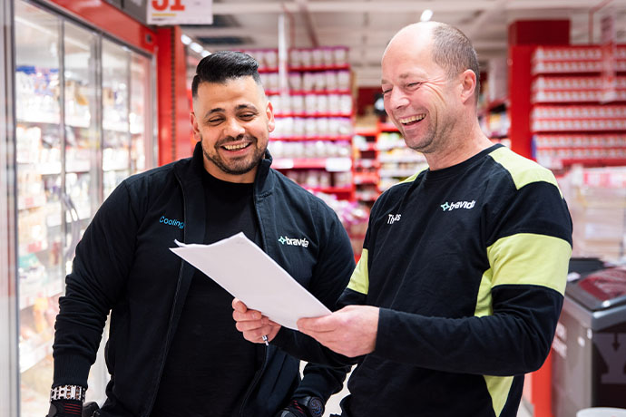 Två kyltekniker under ett samtal i butiksmiljö